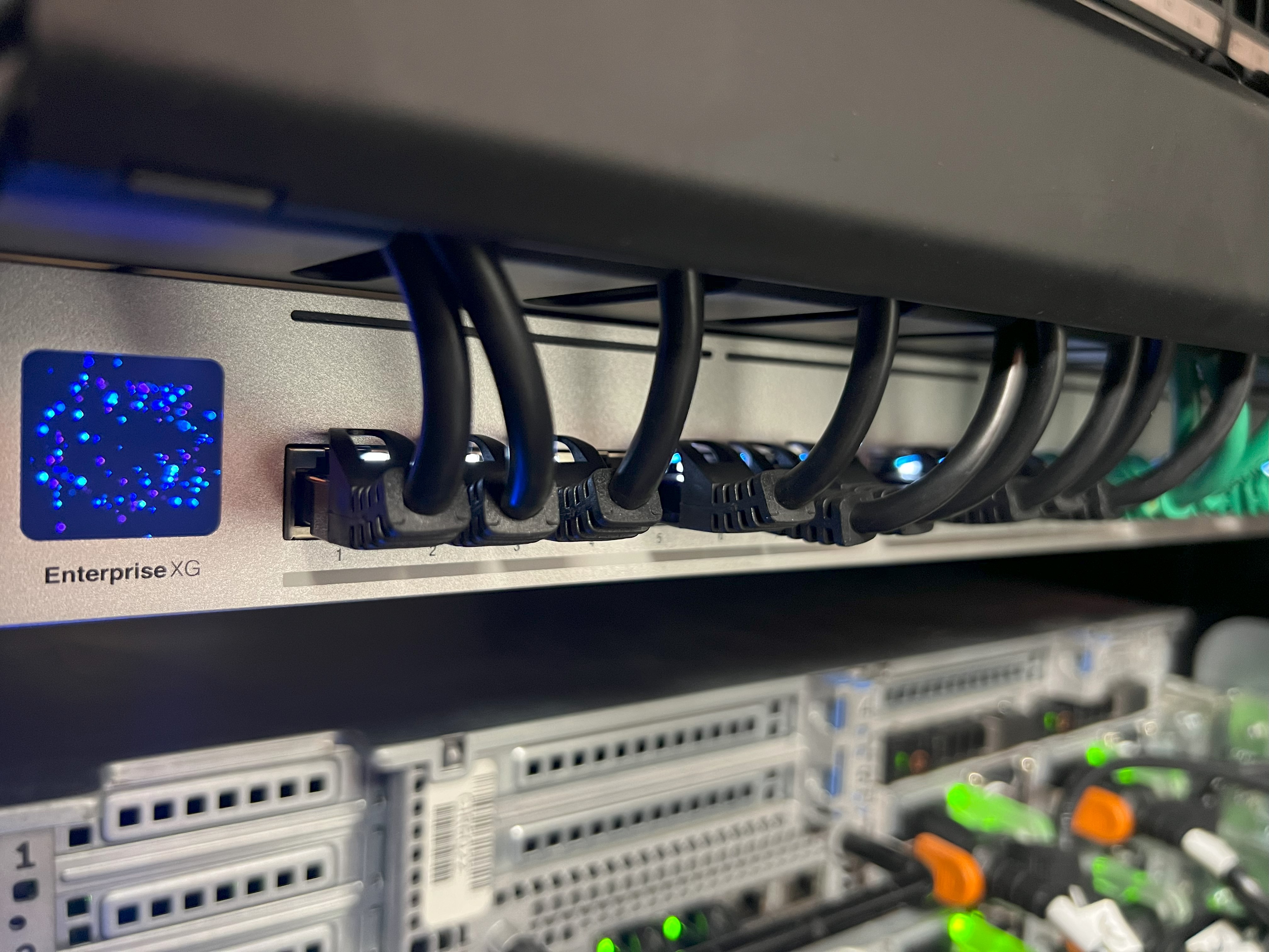 Close-up of a UniFi Enterprise XG network switch with multiple connected Ethernet cables in a server rack.